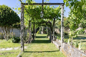 A garden with a pergola structure, stone walls, and a pathway. - Room 'Pospazo I' with Air Conditioning (Cubilledo)