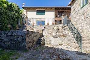 Una escalera de piedra que conduce a un edificio con balcón, rodeado de follaje.