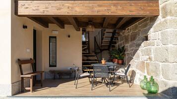 A wooden deck with outdoor furniture, a staircase, and stone walls.