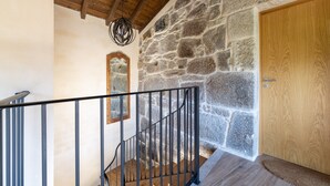 Una escalera con pared de piedra, puerta de madera y barandilla de metal.