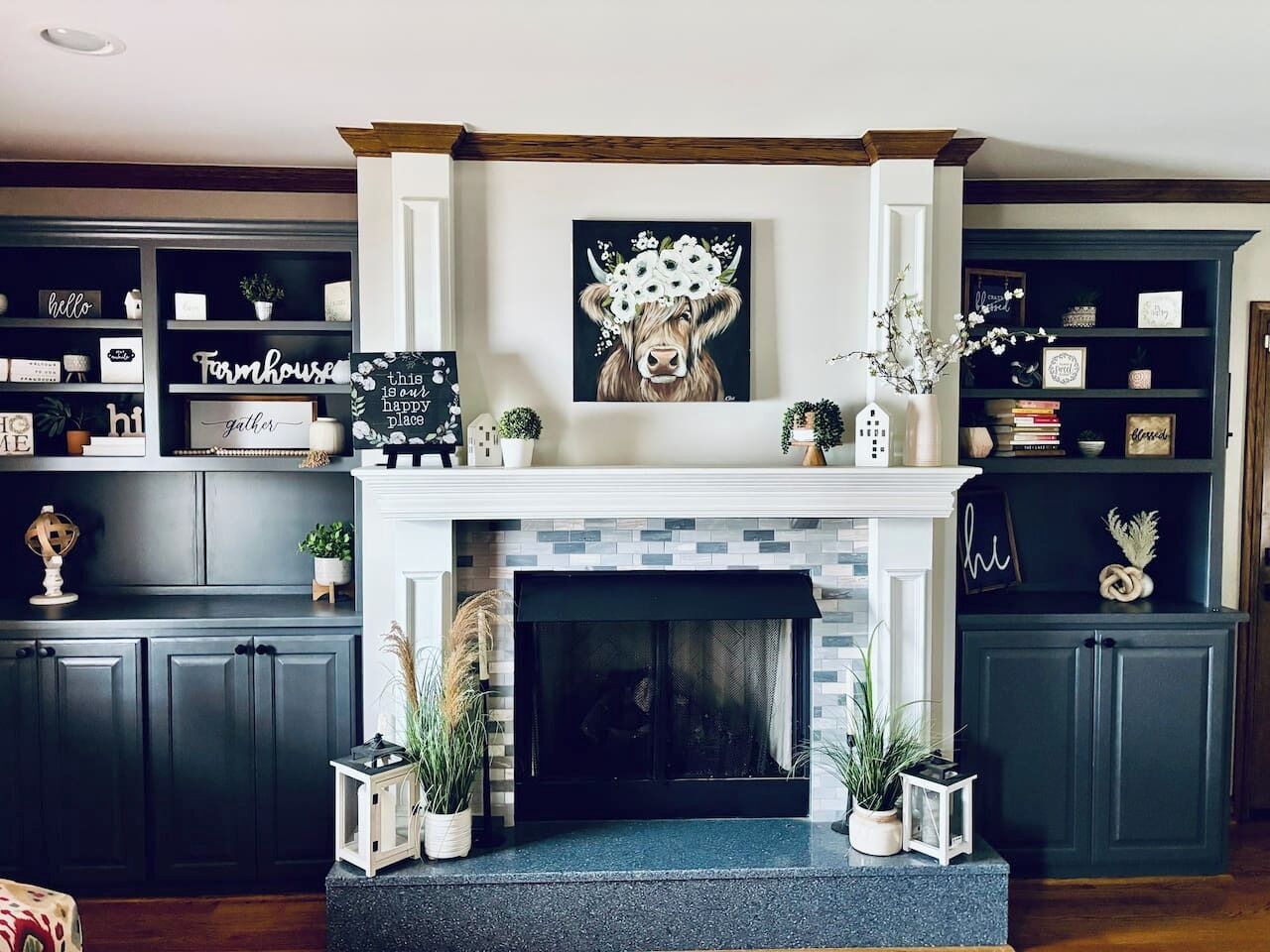 A fireplace with a decorative mantle, flanked by dark cabinets and shelves with various items.