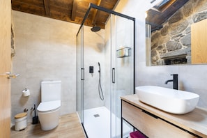 A modern bathroom with a glass-enclosed shower, a white sink, and a stone wall. - CDC 3 Casa do Capitán in nature, with air conditioning and pool (Cubilledo)
