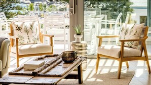 Ein Balkon mit zwei Holzstühlen, einem Tisch mit Tablett und einem Blumentopf.