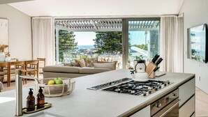 Eine moderne Küche mit einer großen Kochinsel, Essbereich und Meerblick.