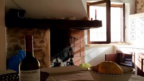 Una botella de vino, un bol de pan y una chimenea en una habitación con ventana y planos arquitectónicos en la pared.
