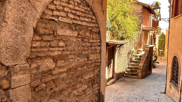 Una estrecha calle adoquinada con un arco de piedra y una escalera que lleva a un edificio.