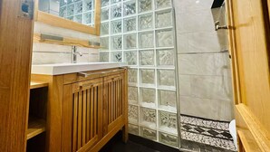 Ein Badezimmer mit einem Holzkosmetikschrank, einer Duschkabine aus Glas und einem gefliesten Boden.