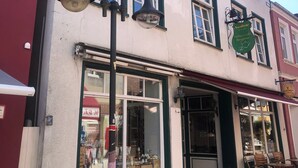 A building with a storefront, large windows, and a sign for a café. - Godewind 1 Apartments with Wi-Fi (Jever)