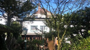 A garden with a statue, a pathway, and a white house with green windows in the background. - Godewind 1 Apartments with Wi-Fi (Jever)