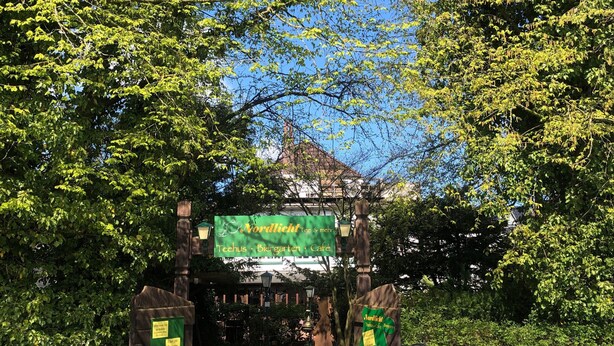 A brick pathway leading to a building with a green signboard. - Godewind 1 Apartments with Wi-Fi (Jever)