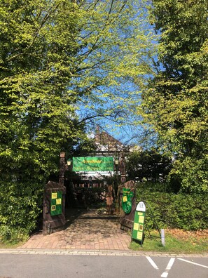 A brick pathway leading to a building with a green signboard.
