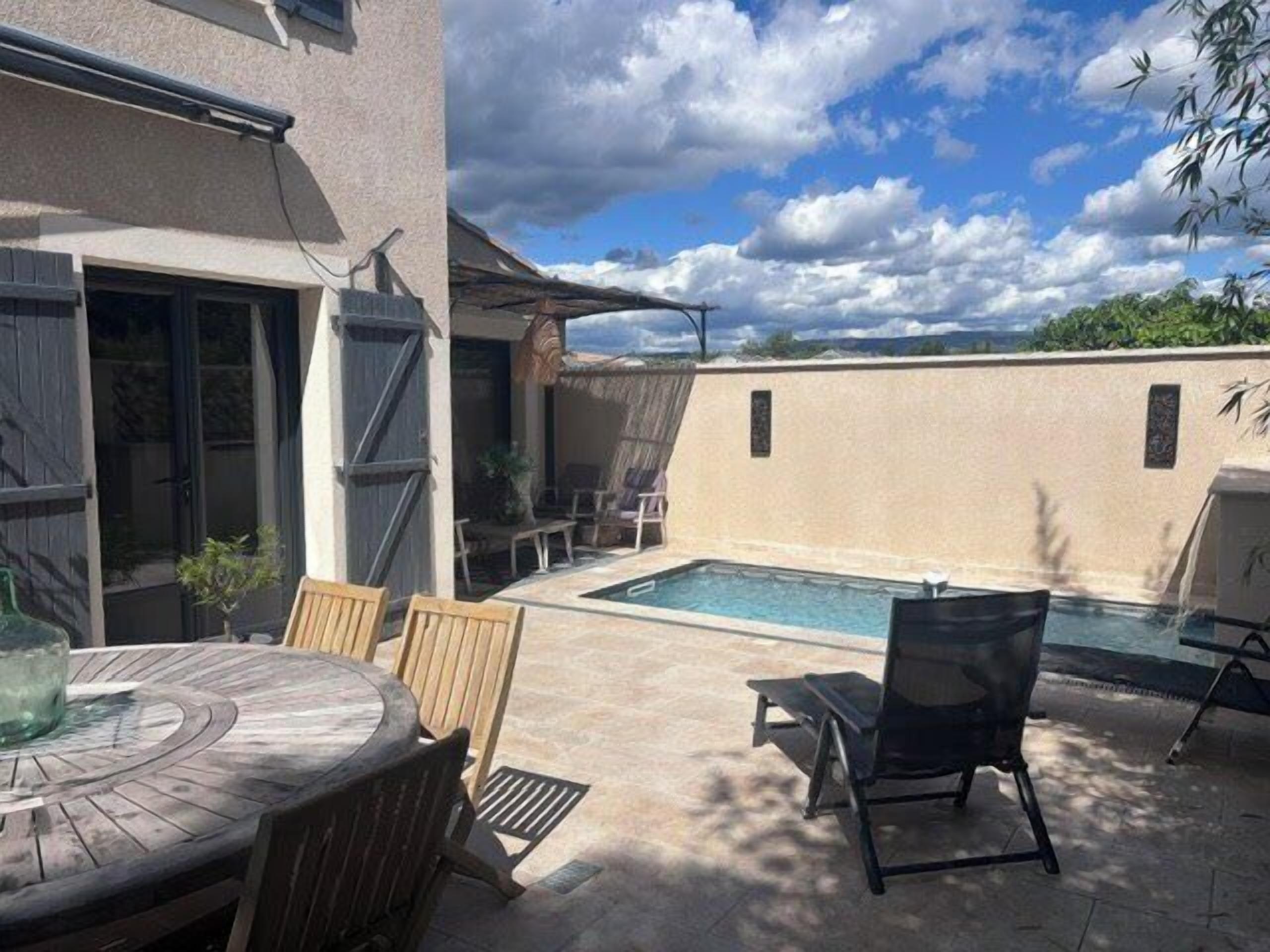 A backyard with a pool, a dining table, and chairs.