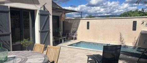 A backyard with a pool, a dining table, and chairs.