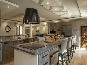 Een moderne keuken met een centraal eiland, barstoelen, een wijnrek en een inbouwoven.