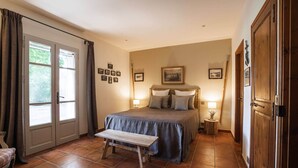 Une chambre à coucher avec un lit, un banc, une porte et une fenêtre.