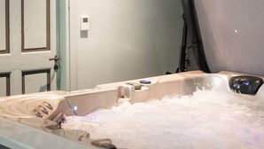 Une pièce avec une baignoire remplie d’eau, une porte et un luminaire au plafond.