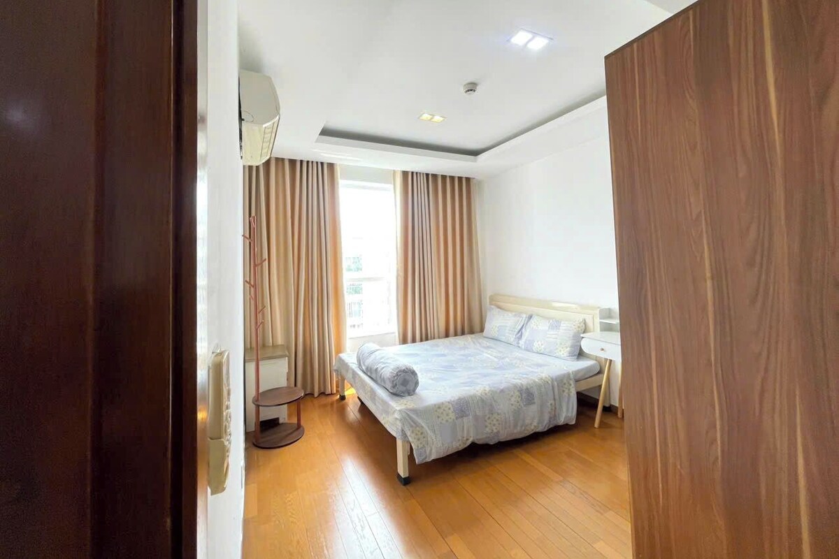 A bedroom with a bed, a bedside table, a lamp, and a window with curtains.
