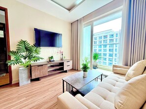 A modern living room with a flat-screen TV, wooden flooring, a sofa, a coffee table, and potted plants. - SKYHOME 2 GIUONG DOI A9 (Ho Chi Minh City)