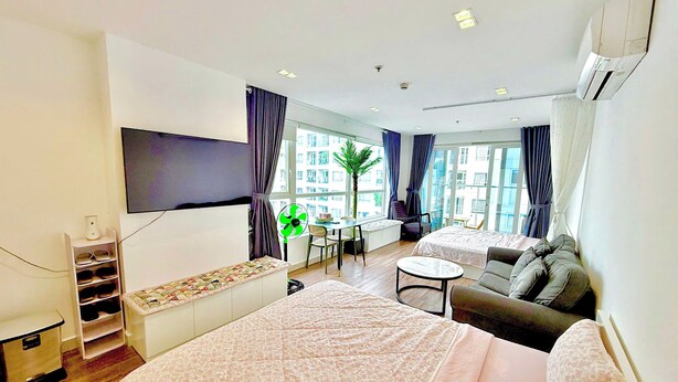 A modern hotel room with a large bed, a sofa, a small table, a TV, and a window with curtains. - SKYHOME 2 GIUONG DOI A9 (Ho Chi Minh City)