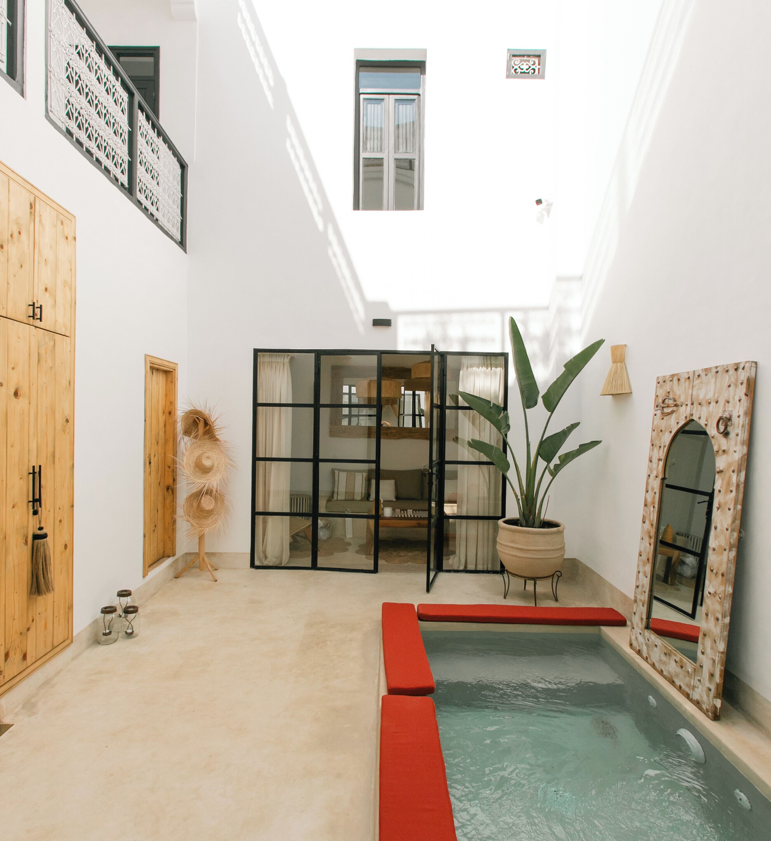 A spacious indoor area with a pool, wooden cabinets, and a large potted plant.