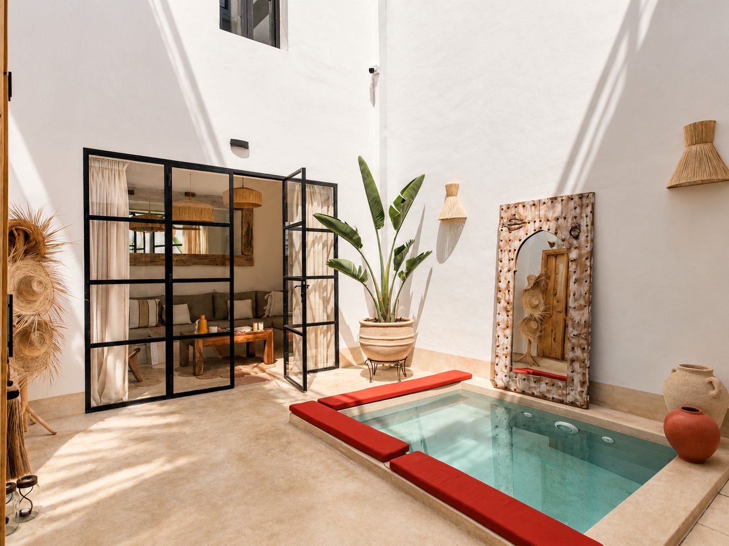 A modern indoor pool area with a glass enclosure, a potted plant, and a decorative mirror.