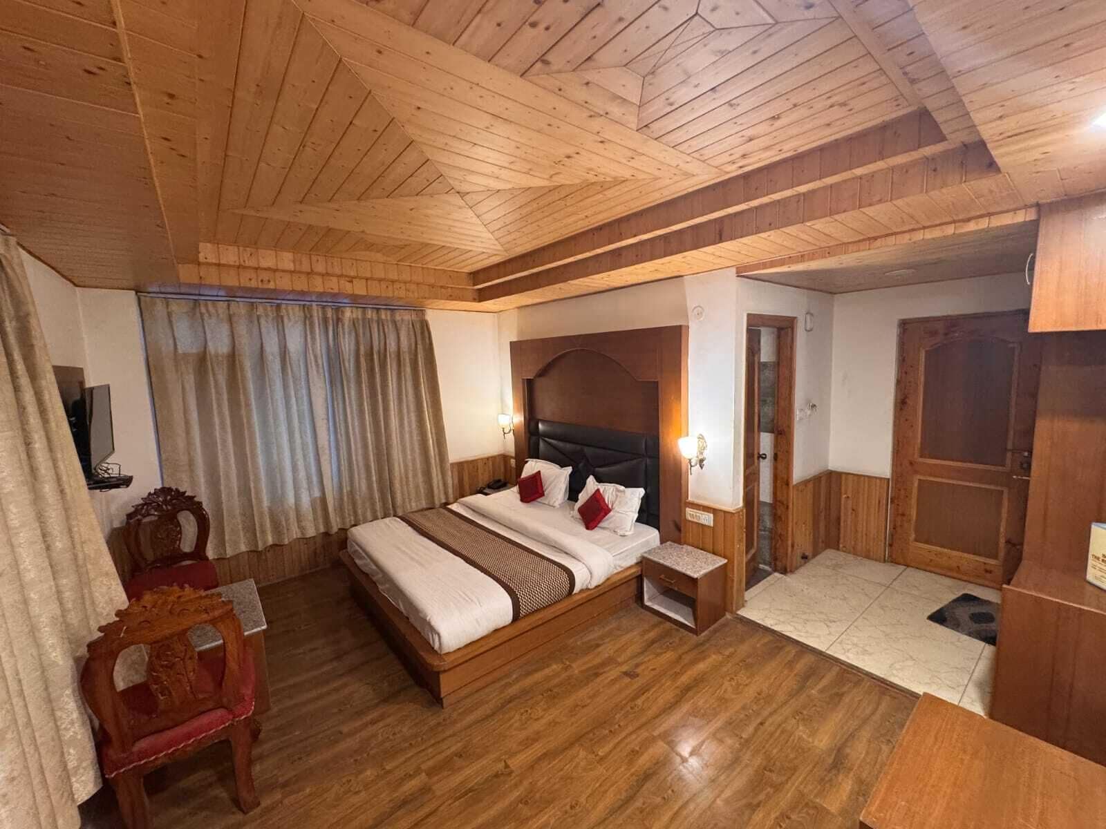 Una habitación con paneles de madera, una cama, mesitas de noche, una silla y una puerta.