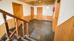 A wooden interior with a staircase, doors, and a fire extinguisher. - Hotel The Red Apple  (Manali)