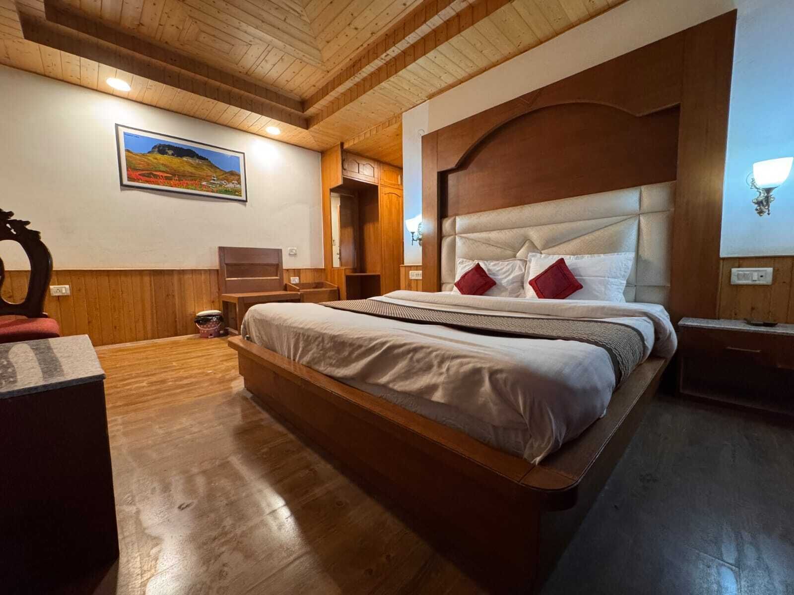 Un dormitorio con estructura de madera, una cama grande, un aparador de madera, un cuadro en la pared y un techo de madera.