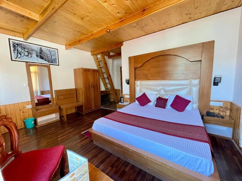 A wooden-framed room with a bed, a wooden chair, a ladder, and a framed picture on the wall.