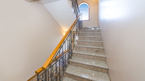 A staircase with a wooden handrail and metal balusters, leading to a landing with a window. - Beachfront Apartment Mareo 4 (Nin)