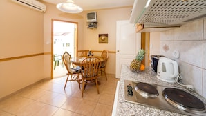 A kitchen with a dining table, chairs, a microwave, a kettle, and a small television on the wall. - Beachfront Apartment Mareo 4 (Nin)