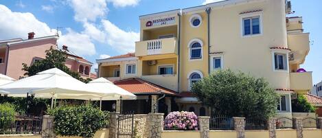 A multi-story building with a restaurant sign, stone walls, and a gated entrance.