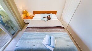 Ein Hotelzimmer mit Bett, Nachttisch, Lampe und Blick ins Freie.