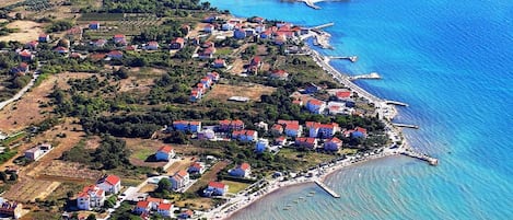 An aerial view of a coastal town with houses, a pier, and a beach.