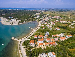 An aerial view of a coastal town with a marina, residential buildings, and a beach. - Beachfront Apartment Mareo 6 (Nin)
