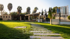 A modern building with a glass facade, surrounded by a well-maintained lawn and palm trees.