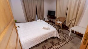 Een hotelkamer met een bed, een televisie, een stoel en een klein tafeltje.
