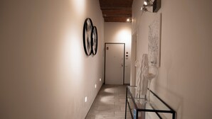 A hallway with a glass table, framed artwork on the walls, and a door at the end. - Happy feelings in Florence (Firenze)