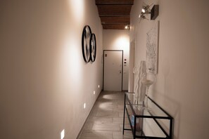 A hallway with a glass table, framed artwork on the walls, and a door at the end. - Happy feelings in Florence (Firenze)