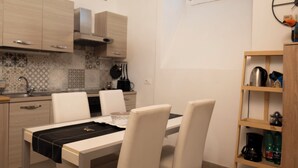 A modern kitchen with a dining table, chairs, pendant lights, and a wooden shelf. - Happy feelings in Florence (Firenze)
