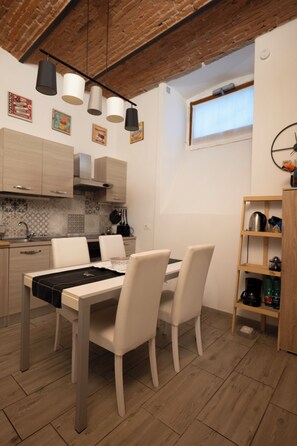 A modern kitchen with a dining table, chairs, pendant lights, and a wooden shelf. - Happy feelings in Florence (Firenze)