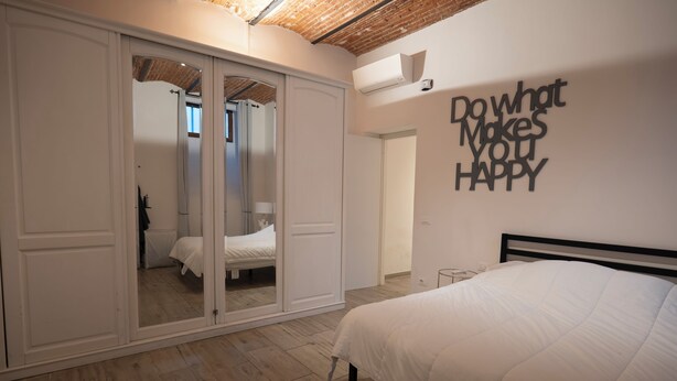 A bedroom with a bed, a wardrobe, and a wall with motivational text. - Happy feelings in Florence (Firenze)