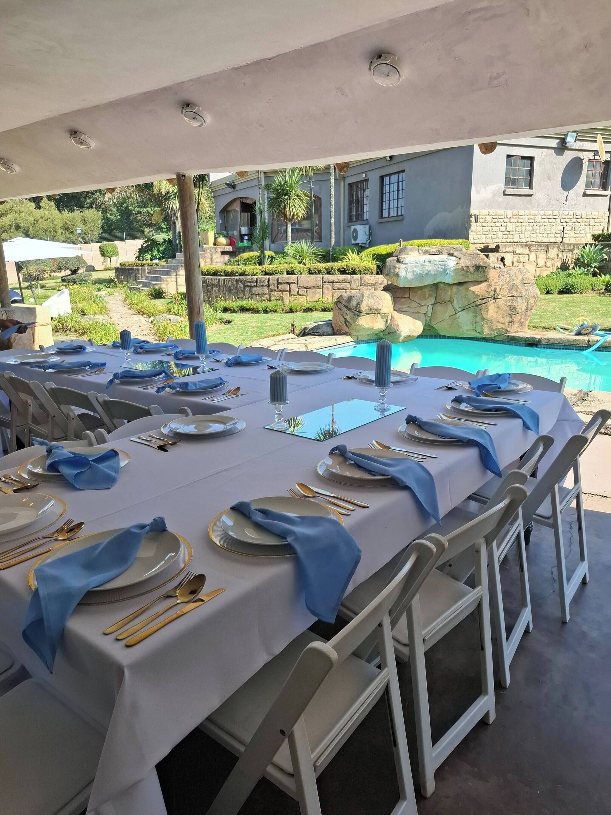 A dining area with tables set for a meal, outdoor seating, and a view of a swimming pool.