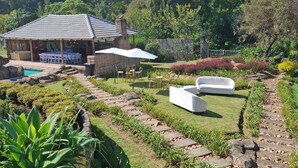 Ein Garten mit Terrasse, Sitzgelegenheiten im Freien und einem Pool.