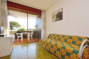 A room with a sofa, a TV, a small table, and chairs. - Cozy Coastal Flat Facing the Port (Lignano Sabbiadoro)
