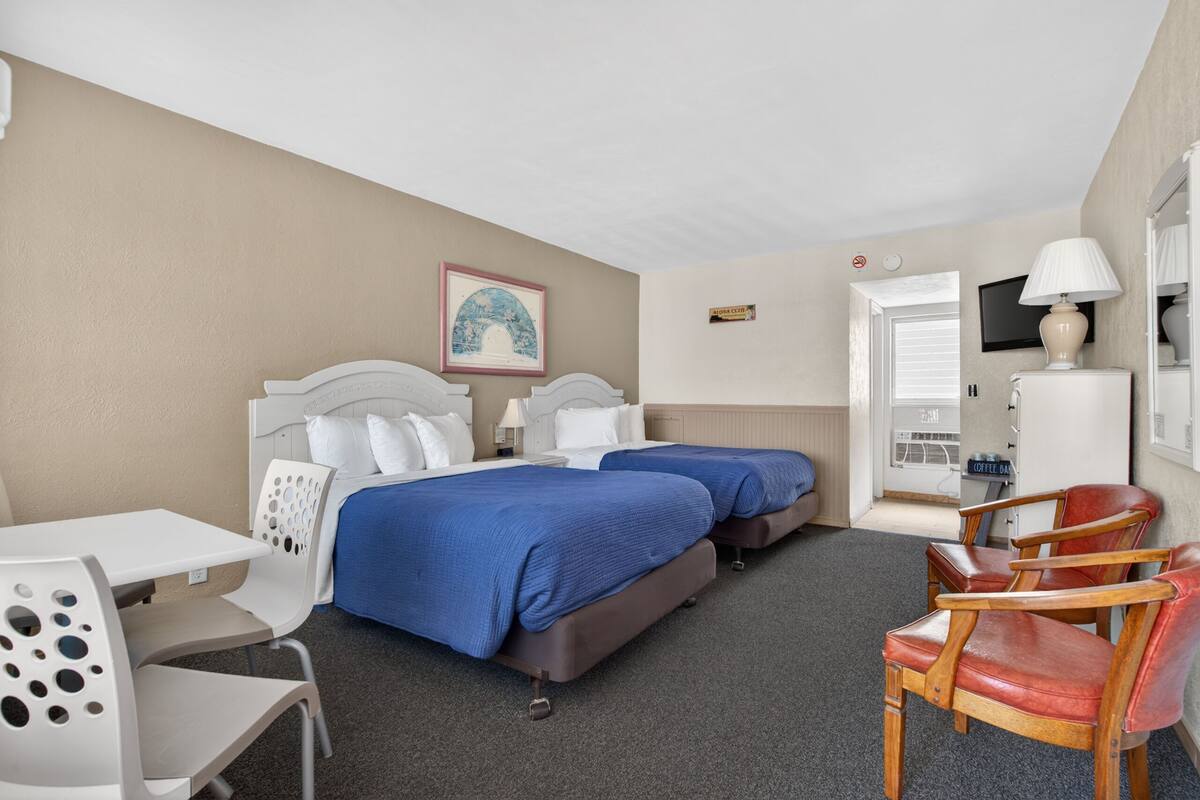 Une chambre d’hôtel avec deux lits, un bureau, une chaise, une télévision et une machine à café.