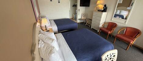 A hotel room with two beds, a TV, a coffee maker, a chair, and a dresser.