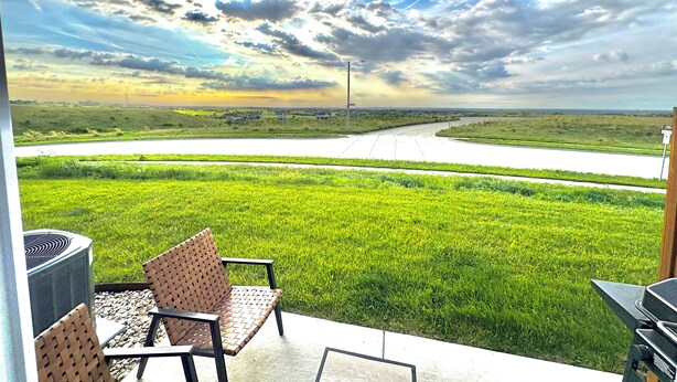 Eine Terrasse mit Gartenmöbeln mit Blick auf eine Straße und Felder.
