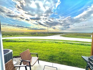 Un patio con mobiliario exterior que da a una carretera y campos.
