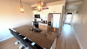 Eine moderne Küche mit Granit-Arbeitsplatten, Edelstahlgeräten und Pendelleuchten.